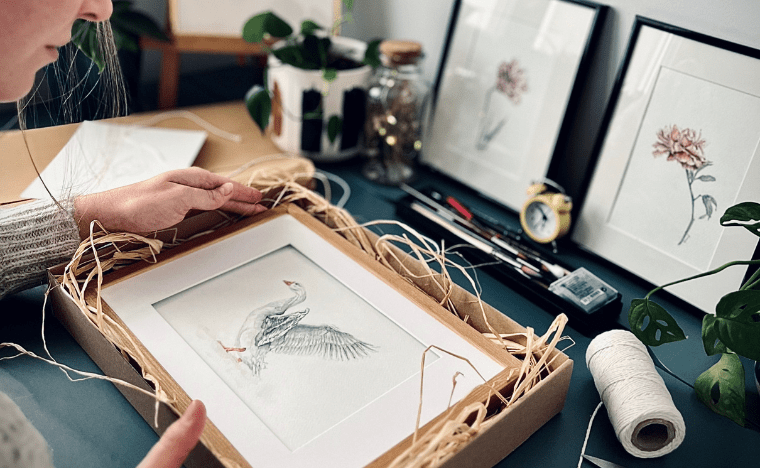 Artystka starannie pakująca obraz do wysyłki