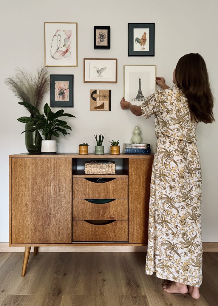 Artist hanging a framed watercolor painting in a wall gallery